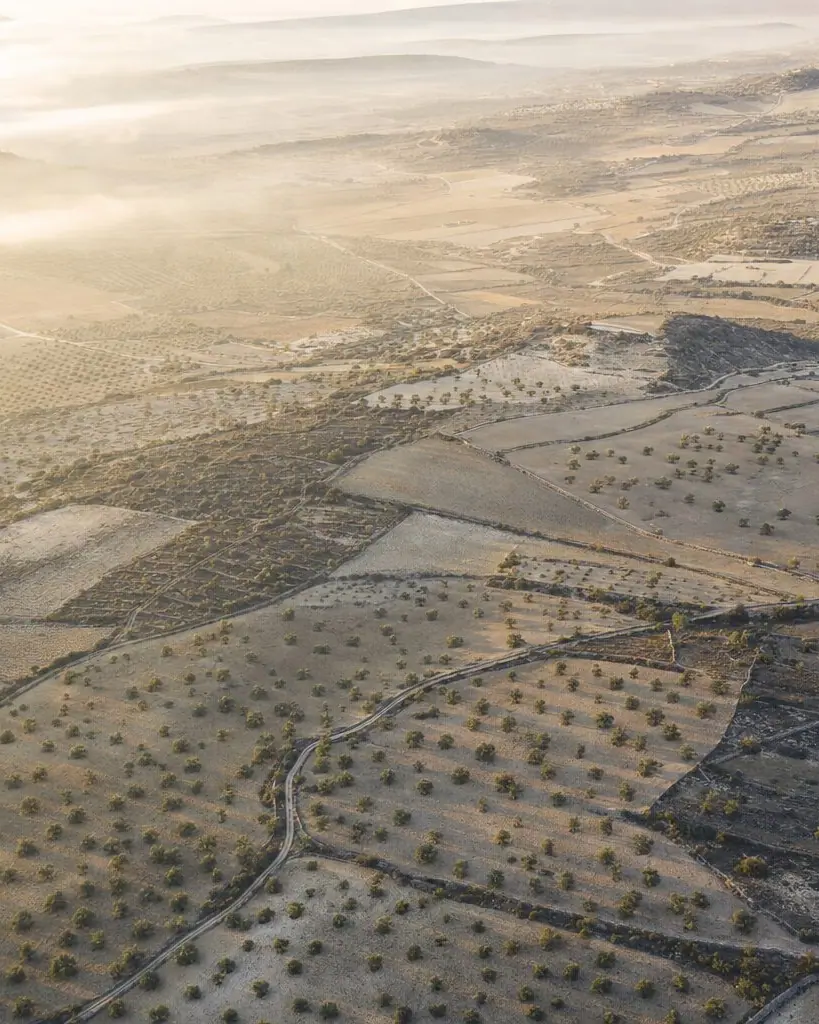 Paisaje aéreo de parcelas agrícolas y terreno mineral divididos por lindes y caminos